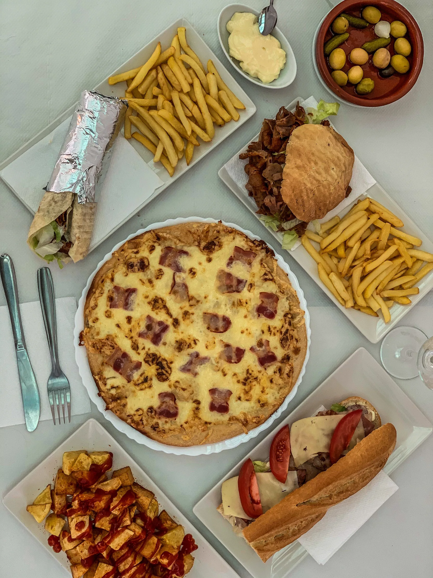 Mesa con pizza, hamburguesa, papas y sándwiches