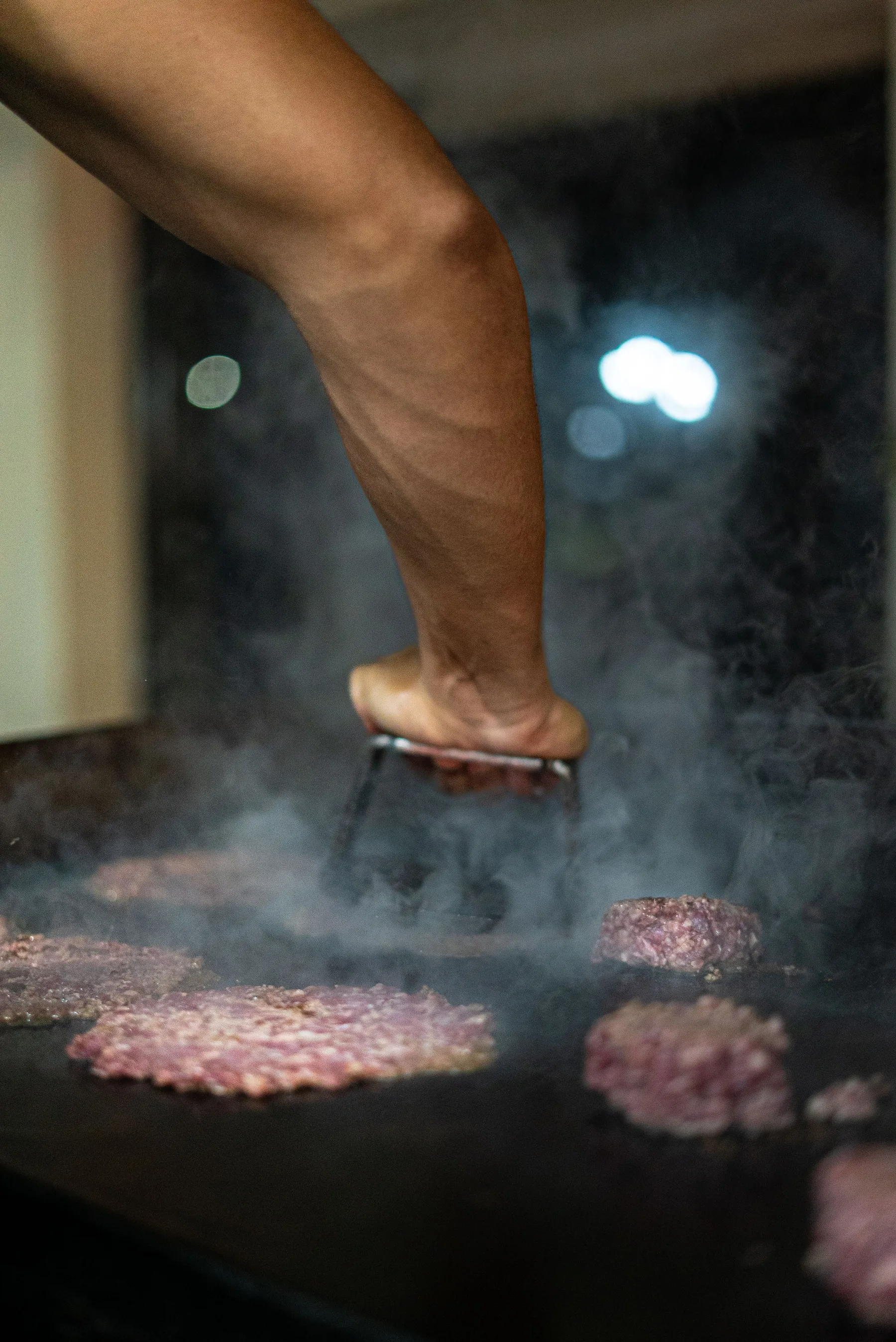 Cocinero preparando hamburguesas a la parrilla